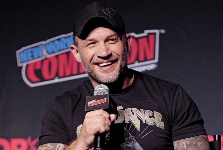 Tom Hardy mentre parla al microfono sorridendo