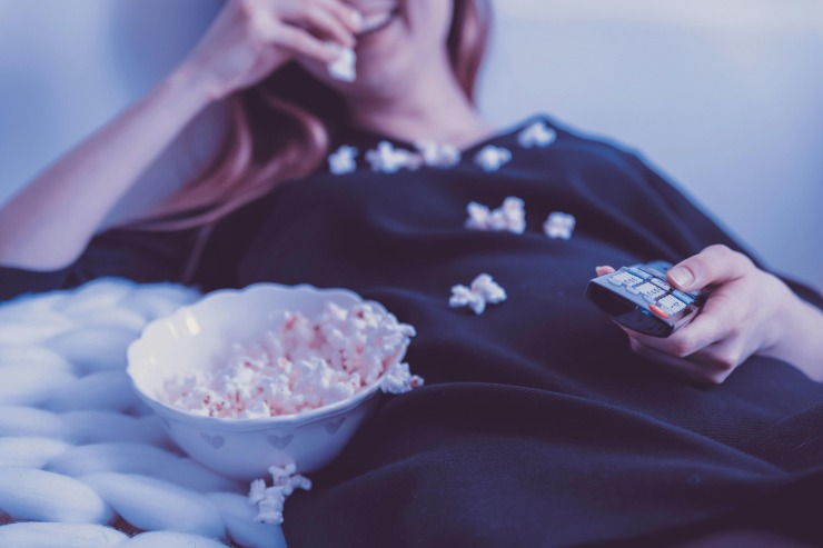 donna guarda la tv mangiando popcorn